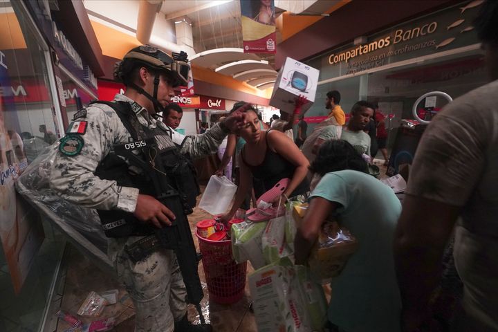 A Mexican National Guard soldier tries to stop looting in a shopping mall after Hurricane Otis ripped through Acapulco, Mexico, on Oct. 25, 2023.
