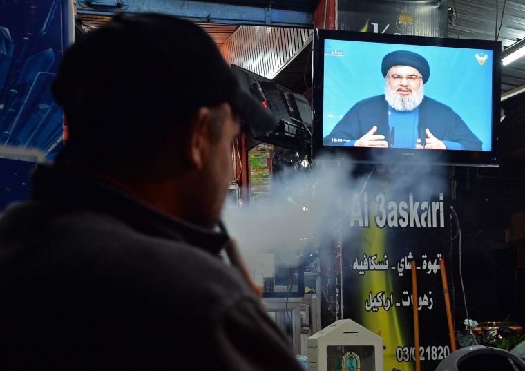 Image: A Hezbollah supporter smokes water pipe as he watches the speech of Hezbollah leader Hassan Nasrallah