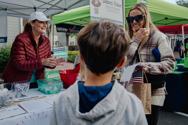 Debra Tisler, left, chats with a mother at her booth at the Clifton Day Festival in Clifton, Va., on Oct. 8, 2023.