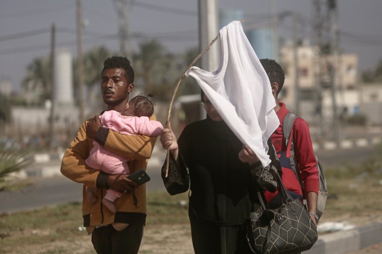 A woman holds-up a white T-shirt as Palestinians flee to the southern Gaza Strip from Bureij, central Gaza, on Tuesday, Nov. 7, 2023.