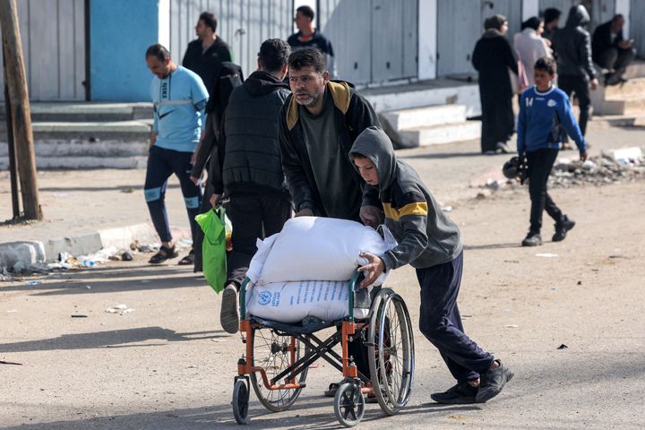 A man and a boy push a wheelchair carrying sacks of flour that their family received from a warehouse of the U.N. Relief and Works Agency for Palestine Refugees (UNRWA) in Rafah in the southern Gaza Strip on Tuesday, amid continuing battles between Israel and the militant group Hamas.