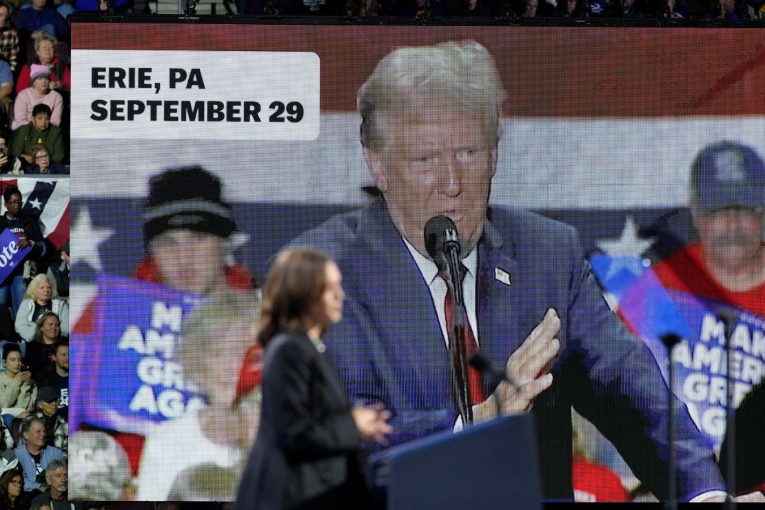 An image of former President Donald Trump appears on screen as Vice President Kamala Harris speaks during a campaign rally in Erie, Pennsylvania, on October 14, 2024.